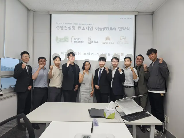회의실에서 여러 명이 함께 서서 기념 촬영한 모습